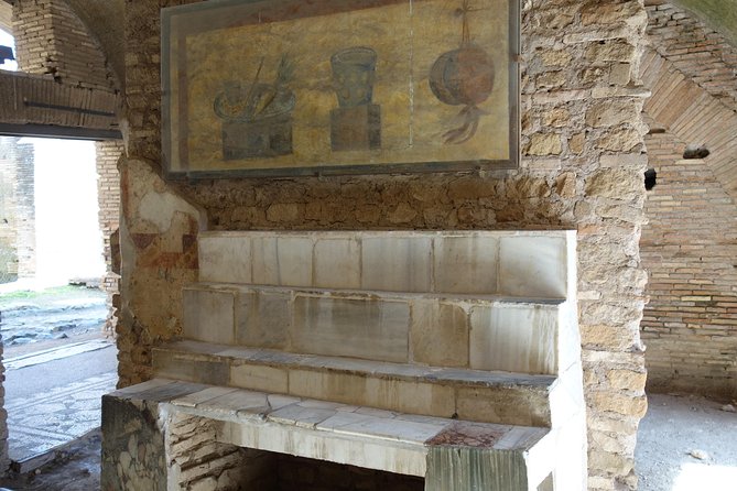 Ancient Ostia Antica Semi-Private Day Trip from Rome by Train with Guide - Amphitheater Views and the Weight of Port-City Entertainment